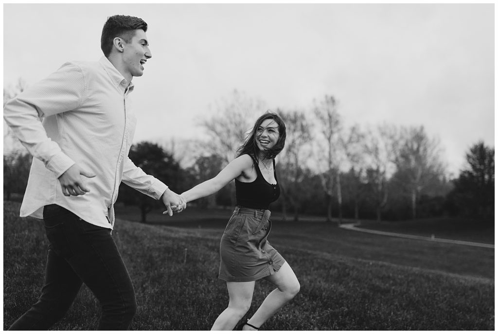 couple pose running together in an open field