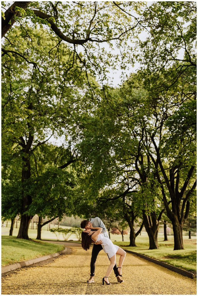 couple pose dipping and kissing in a tunnel of trees