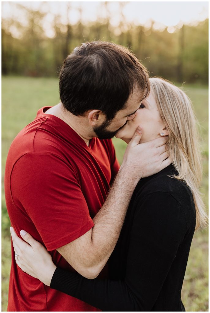 couple pose kissing with hand on cheek 