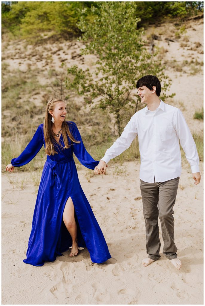 couple pose walking on beach holding hands