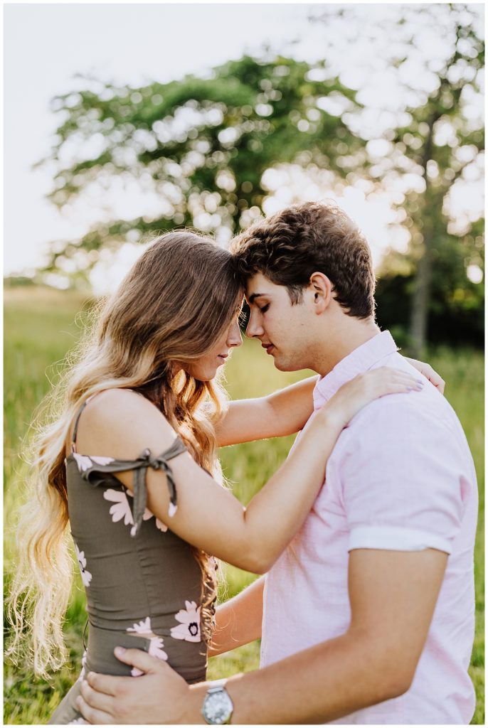 couple touching foreheads toghether hugging in field of grass