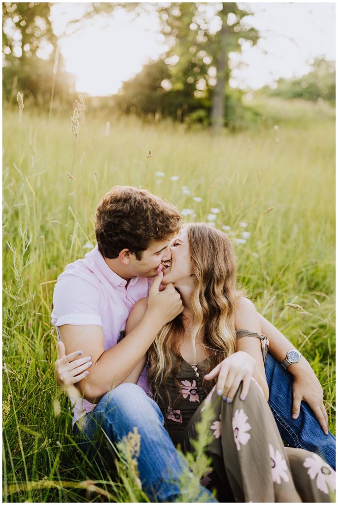 couple laughing and kissing in field of grass