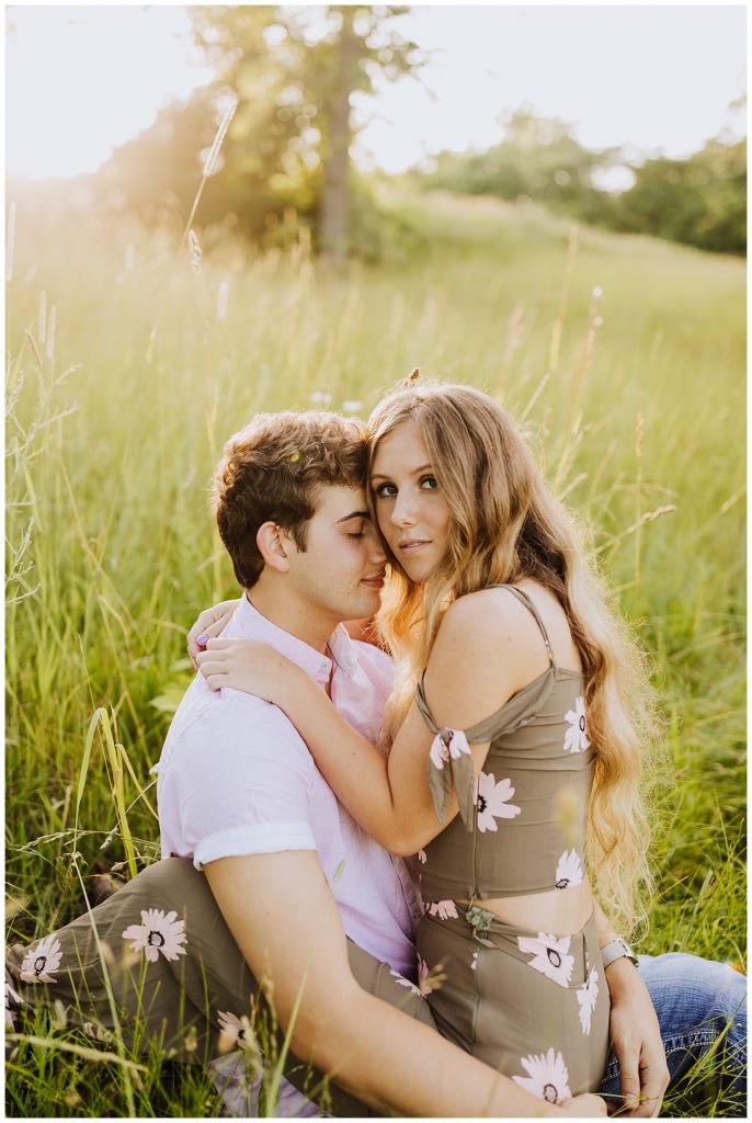 couple sitting in field of grass during sunset