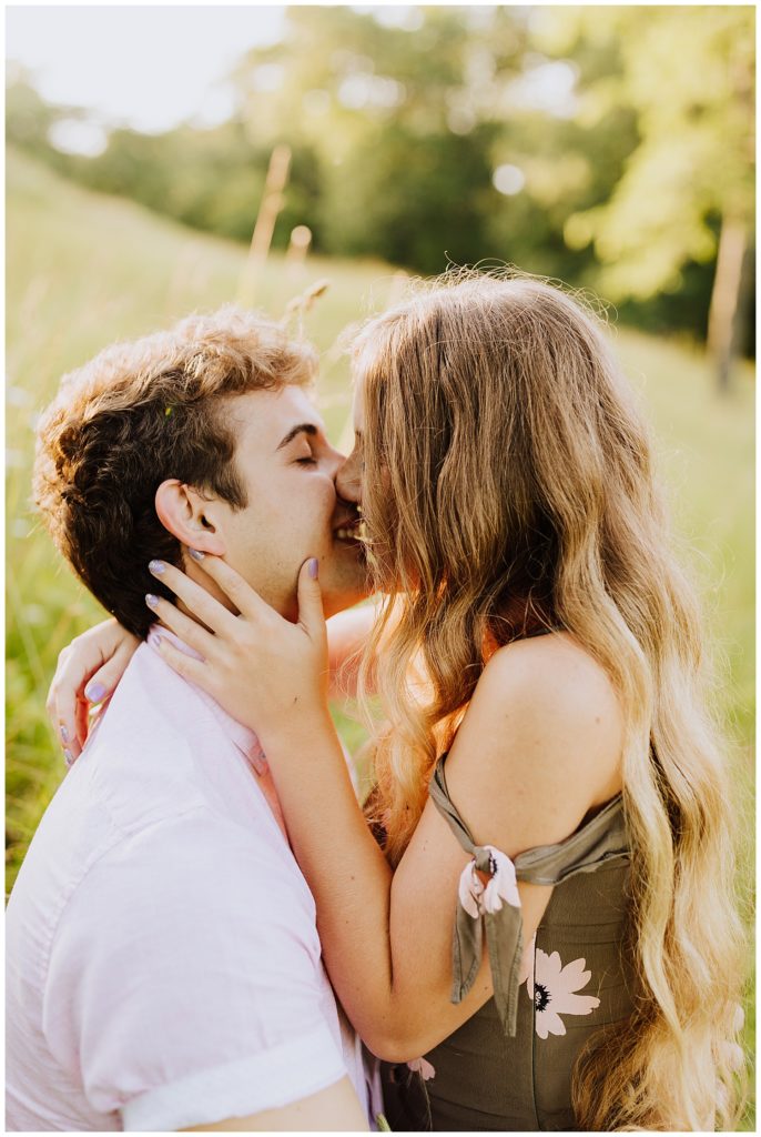 couple kissing in field of grass during sunset