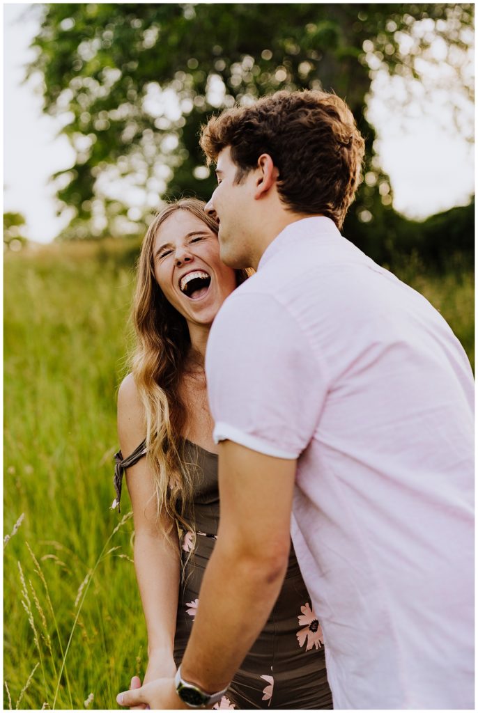 couple laughing in field of grass during sunset
