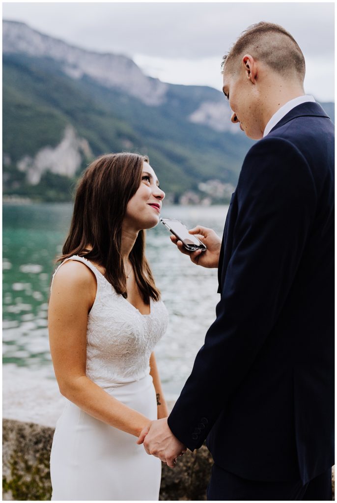 bride and groom saying vows in front of mountains and lake annecy france