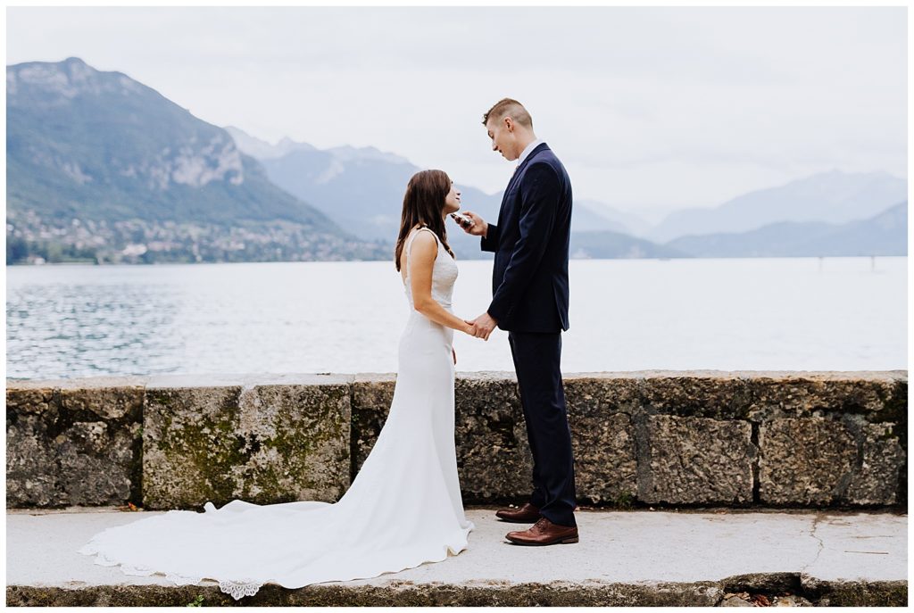 bride and groom saying vows in front of mountains and lake annecy france