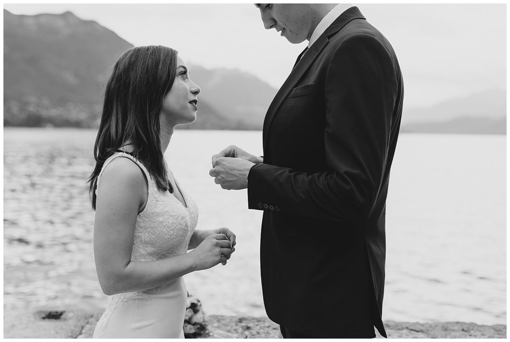 bride and groom exchanging rings in front of mountains and lake in annecy france