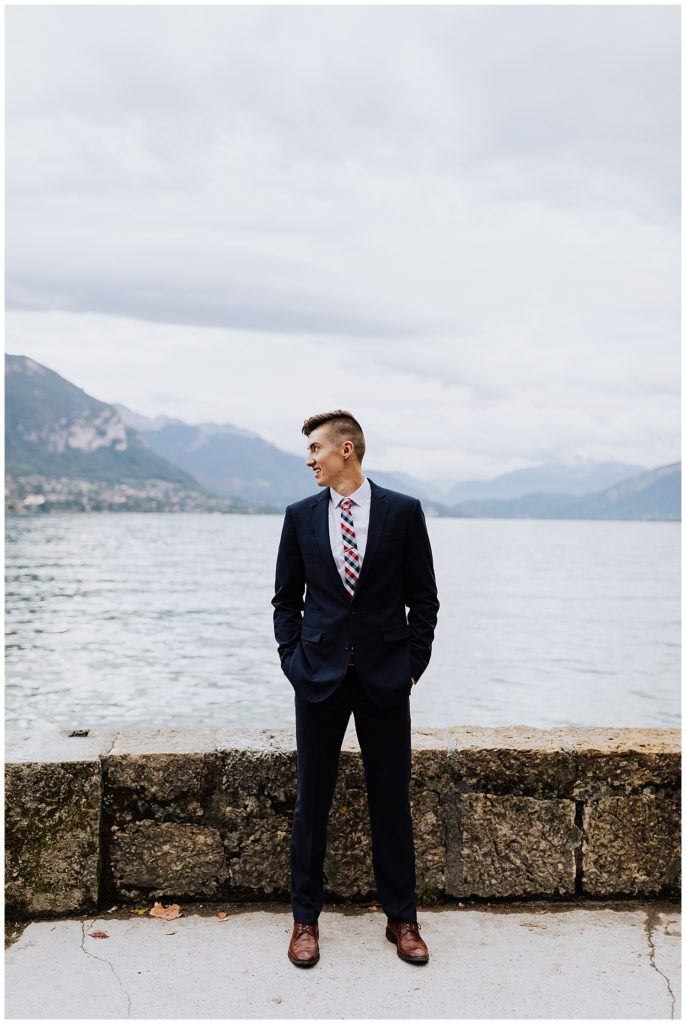 groom in front of mountains and lake in annecy france