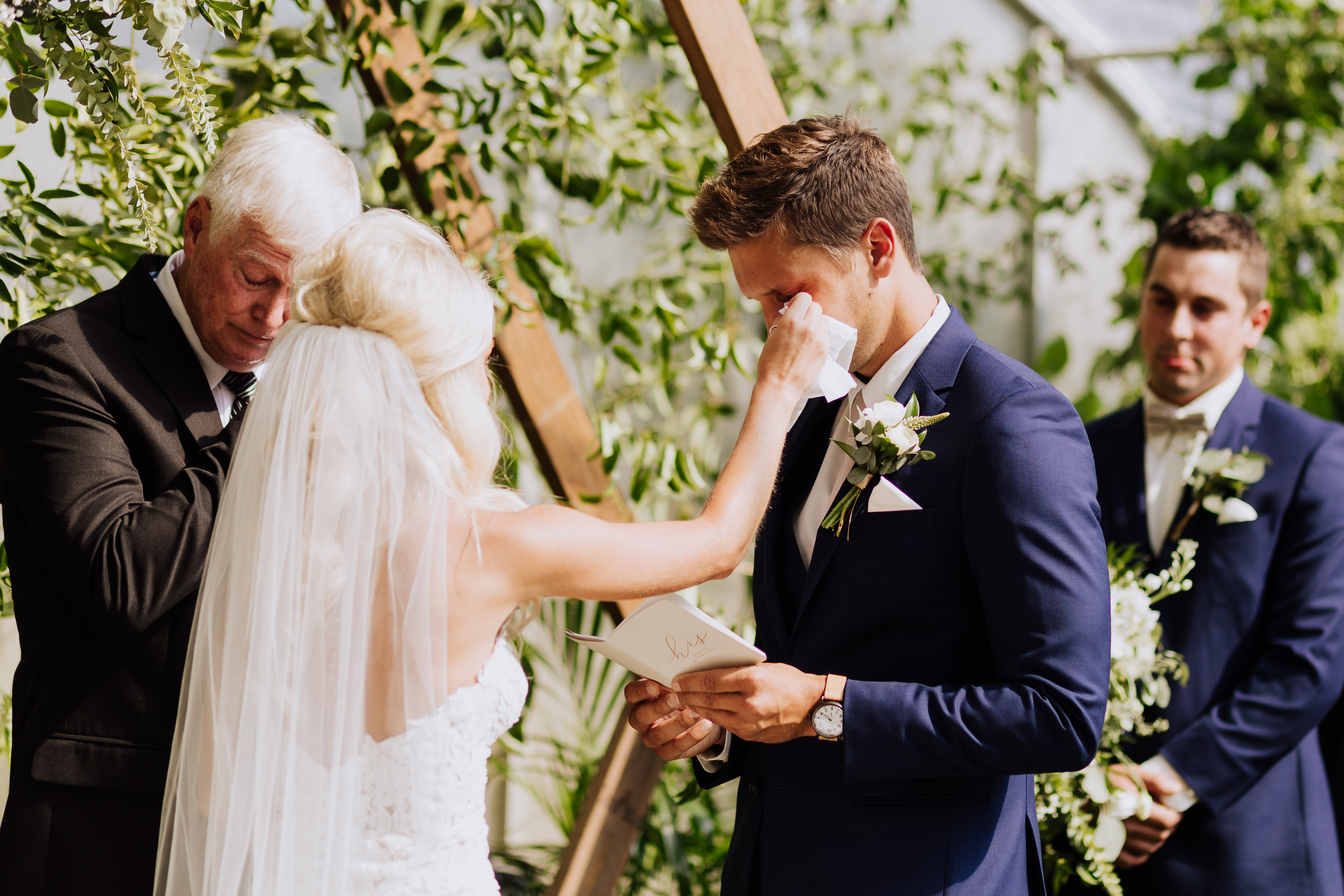 bride wiping groom's tears while saying his vows