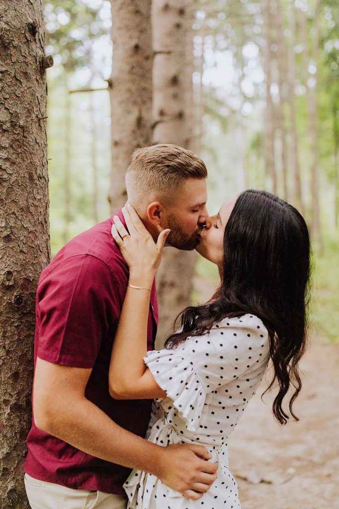 couple kissing up against a tree