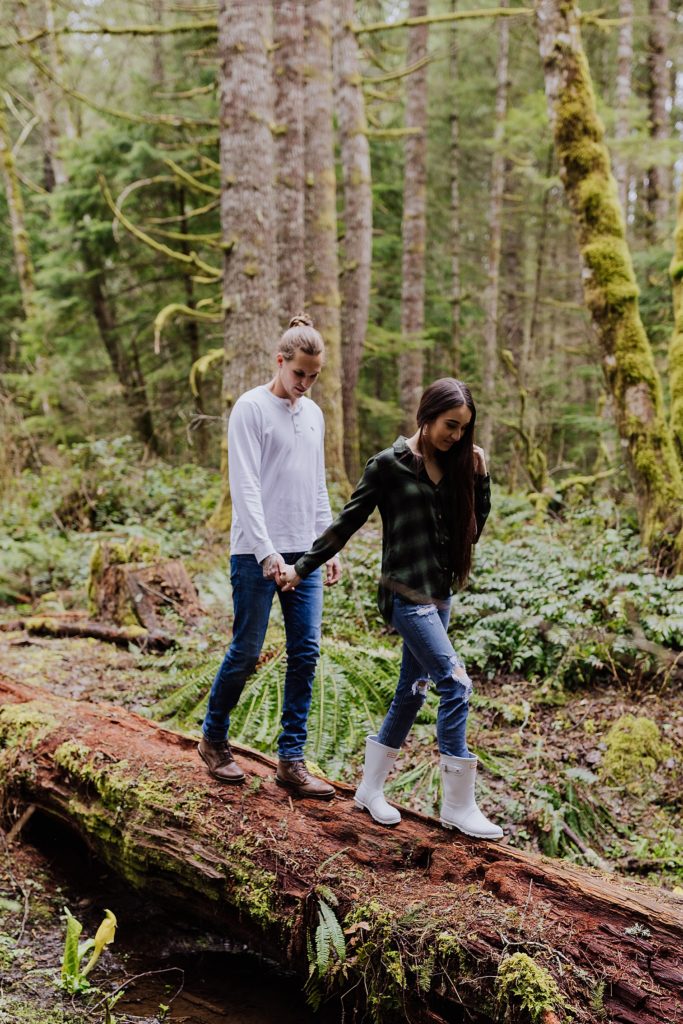 oregon couple walking through the woods holding hands