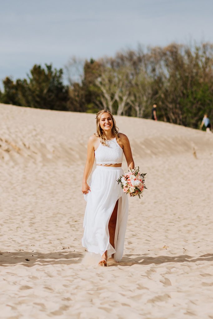 bride holding flowers walking on the beach