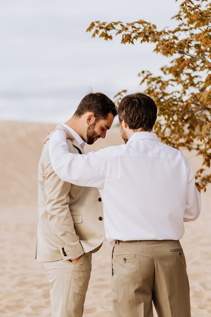 officiant and groom praying before ceremony on beach
