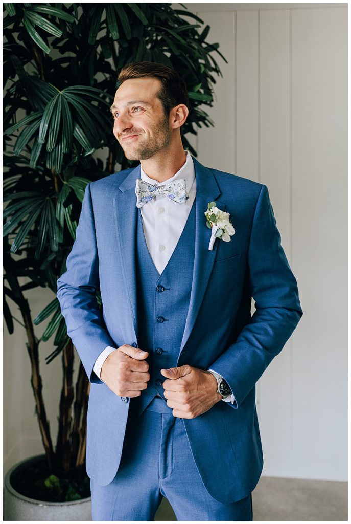 Groom smiles looking out of window by Kayla Bouren Photography