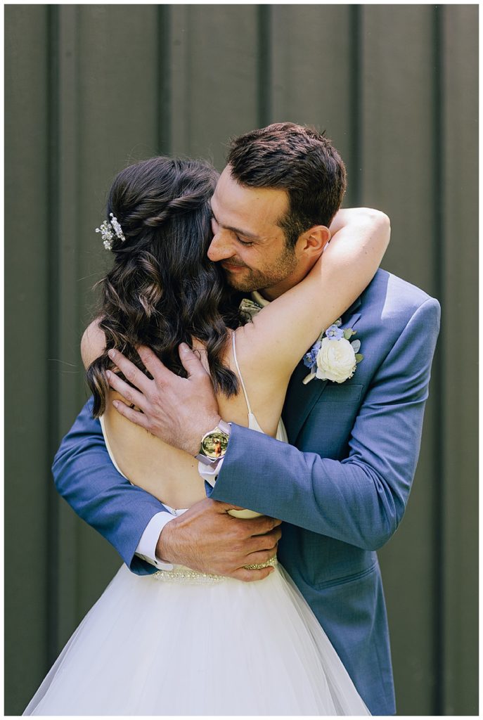 Groom hugs bride by Kayla Bouren Photography