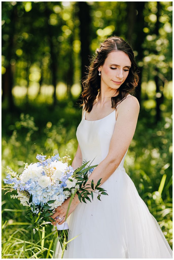 Bride smiles looking down with bouquet by Kayla Bouren Photography