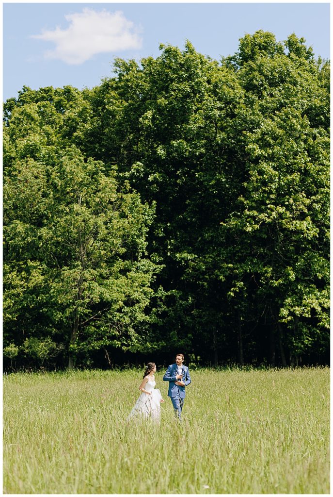 Bride and groom walk in green pasture Kayla Bouren Photography