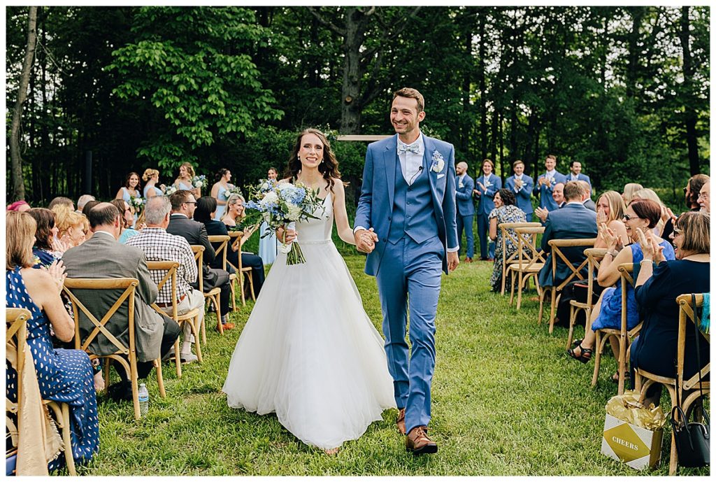 All smiles and cheers as couples walks down aisle by Kayla Bouren Photography