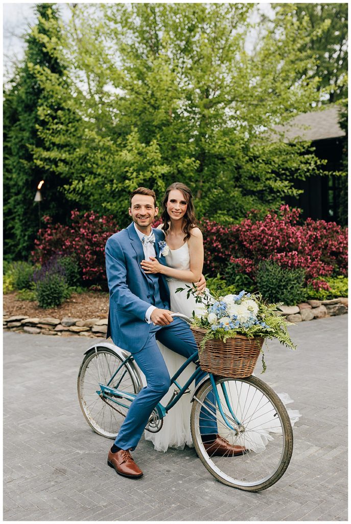 Groom is on bike with bride beside by Kayla Bouren Photography