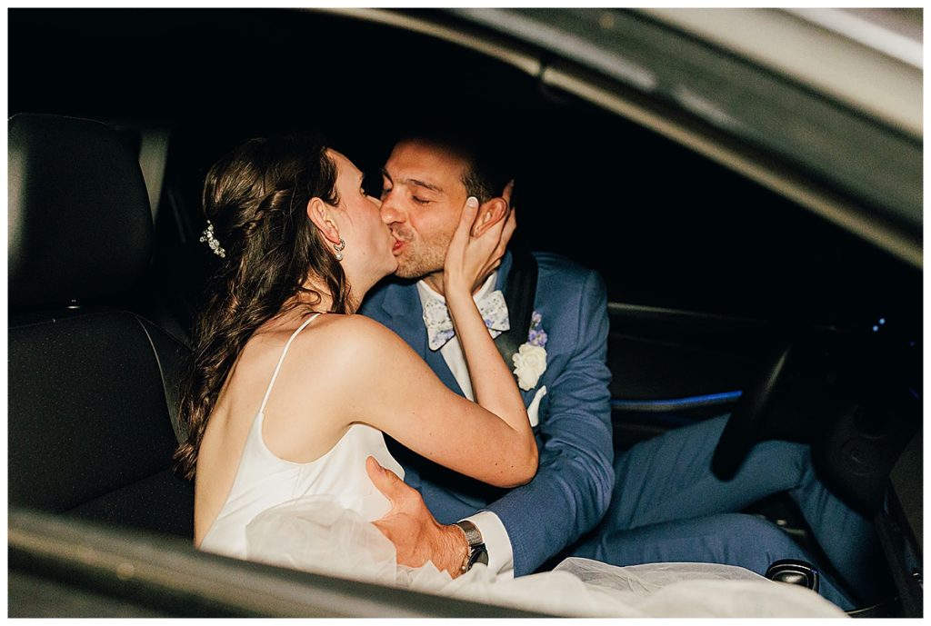 During evening car ride bride and groom kiss at Cushing Field House wedding