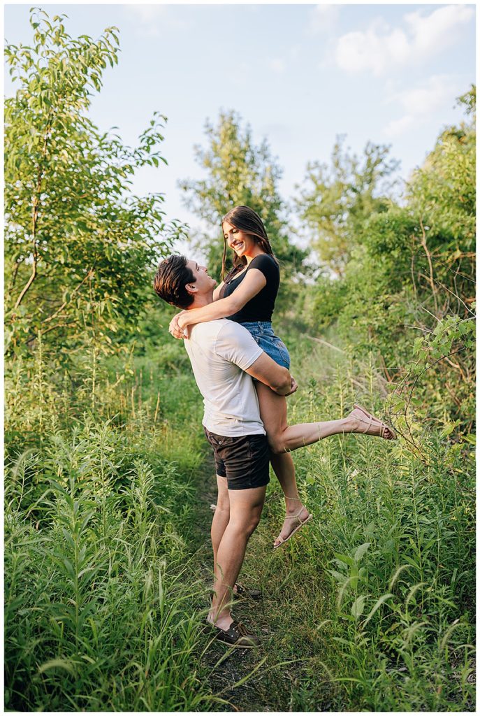 Man picks up woman in green field for Kayla Bouren Photography