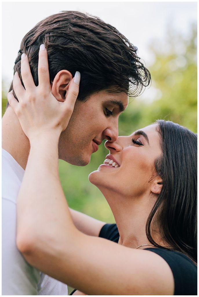 Woman holds mans face and smiles for Kayla Bouren Photography