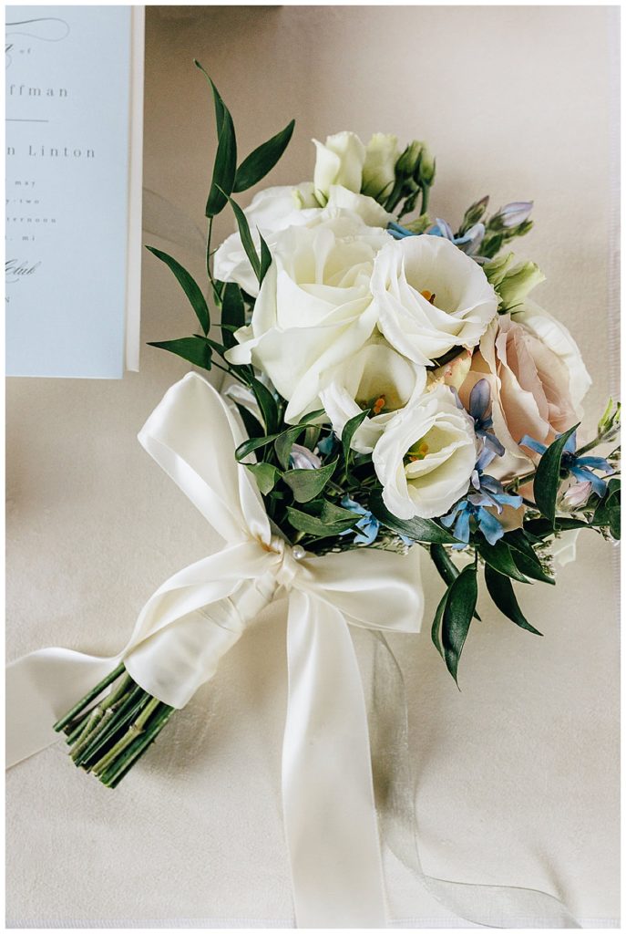 Bridal bouquet is wrapped in beautiful white fabric next to stationery suite by Kayla Bouren photography.