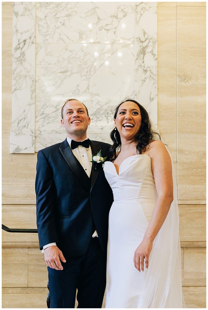 Couple share hug and look out with smiles after first look in stairwell by Detroit Wedding Photographer.