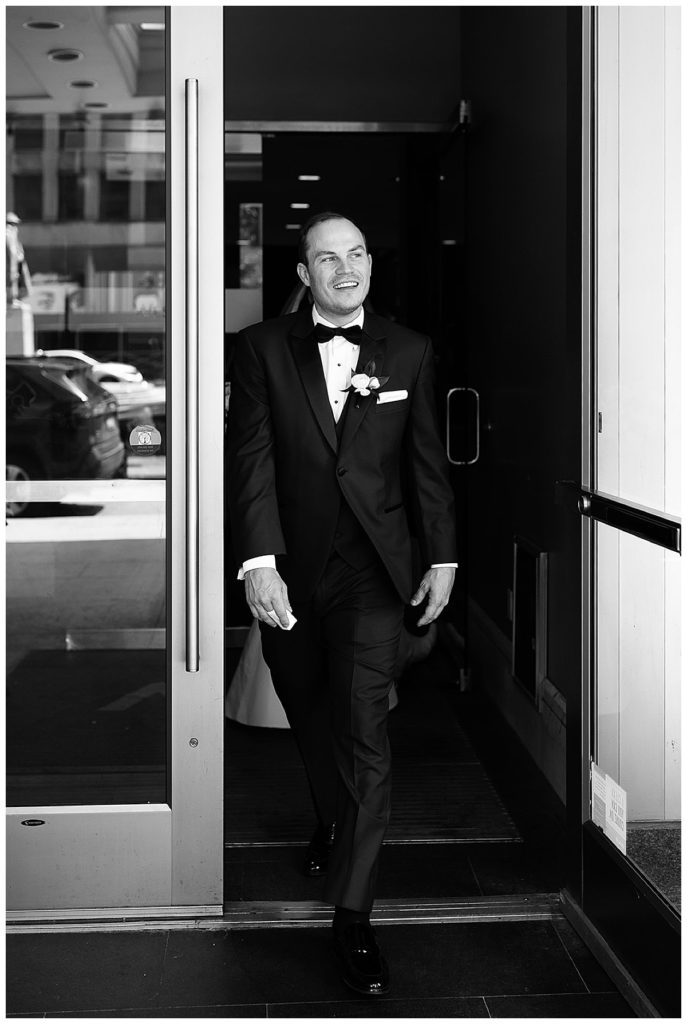 Groom is walking out the building by Kayla Bouren photography.