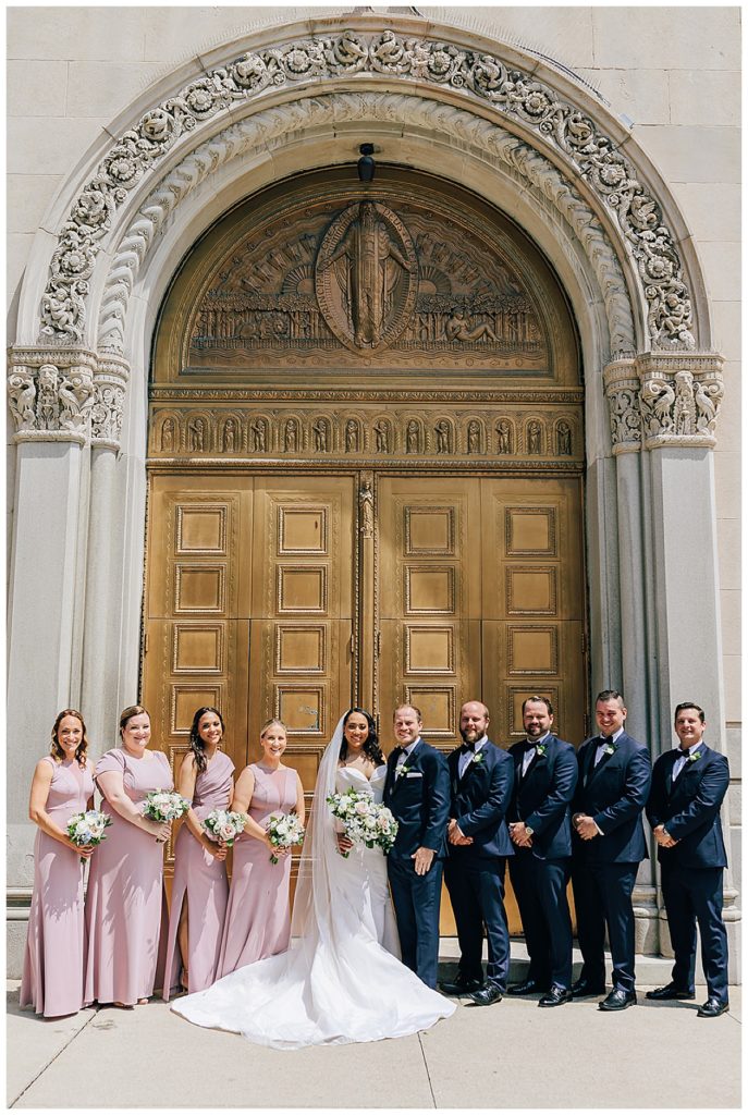 The entire wedding party is surrounding the couple with smiles by Kayla Bouren photography.