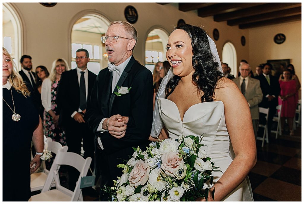 Father of the bride is smiling with bride as he walks her down the aisle by Detroit Wedding Photographer.