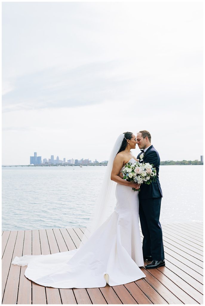 In front of the Detroit skyline and water, the bride and groom share a special moment by Kayla Bouren photography.