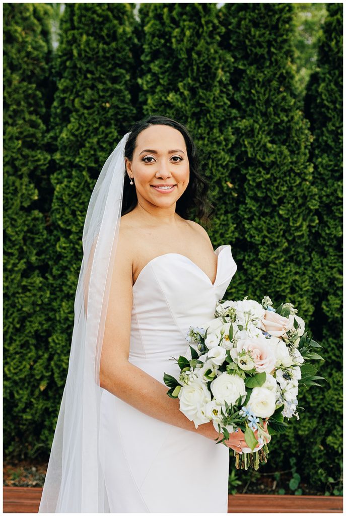 Holding her bridal bouquet, the bride is smiling big in her bridal gown by Kayla Bouren photography.