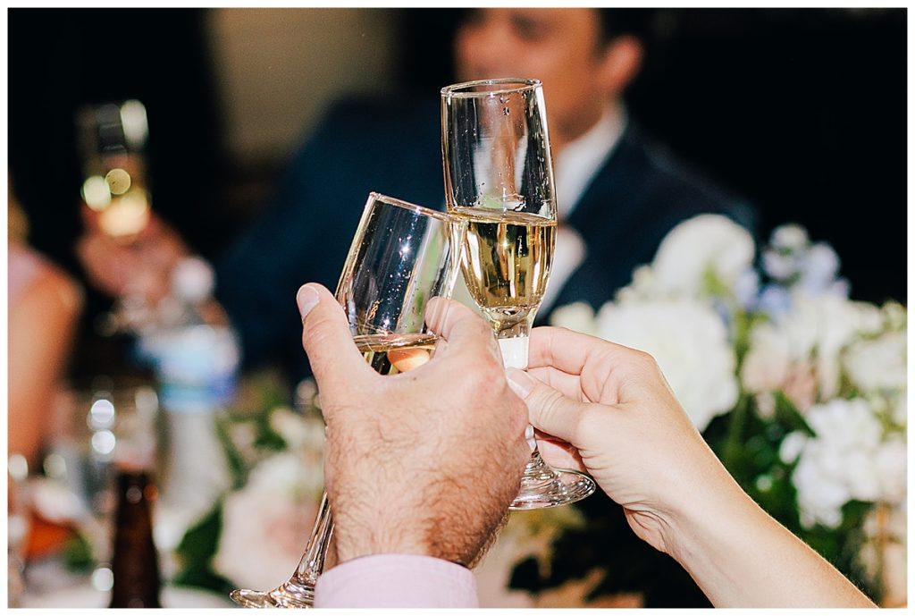 Champagne filled glasses touch to celebrate the new Mr. & Mrs. by Kayla Bouren photography.