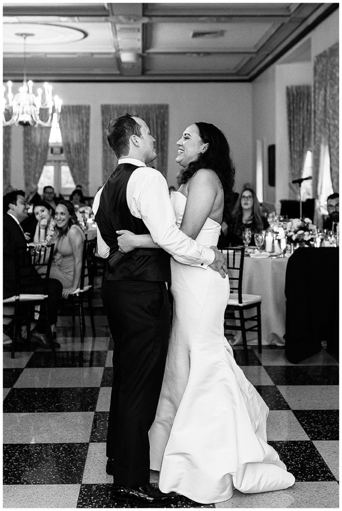 New husband and wife share first dance laugh and smiles together at elegant Yacht Club wedding.