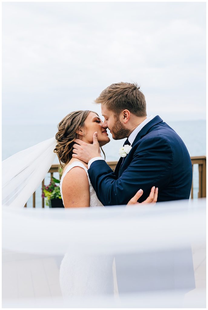 Groom kisses bride by Detroit wedding photographer