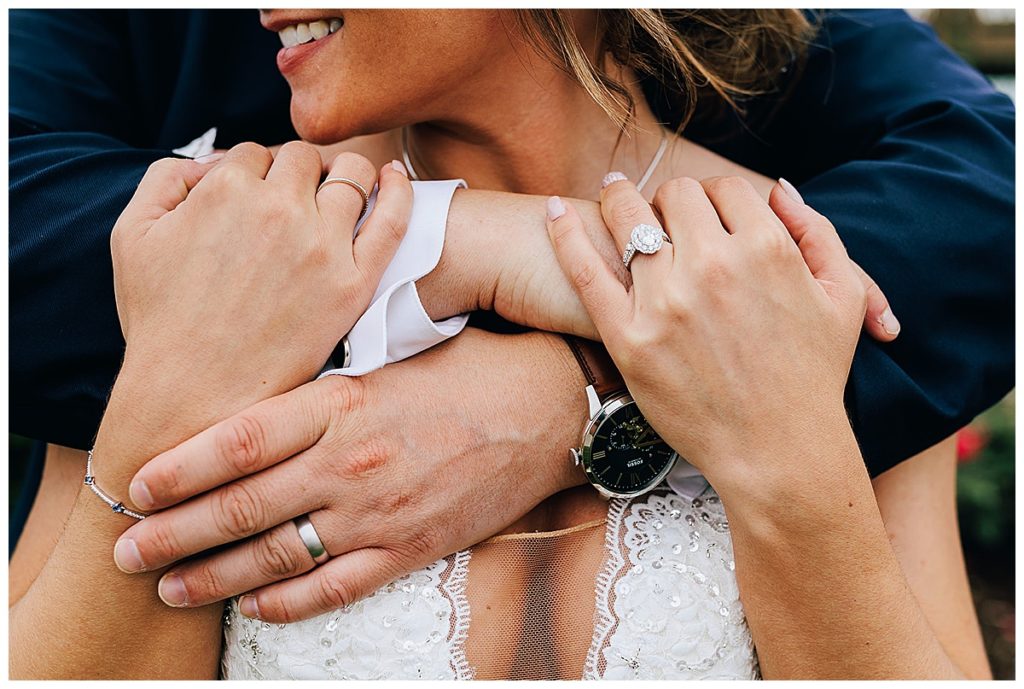 Groom embraces bride with wedding rings by Kayla Bouren Photography.