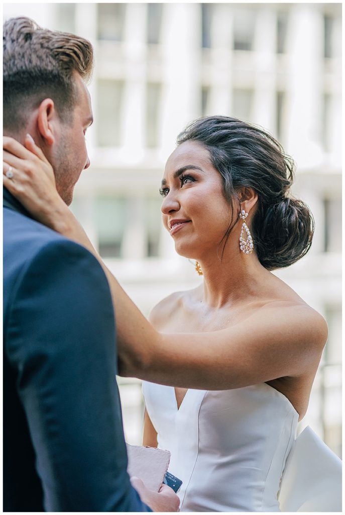 Bride holds groom face in love by Kayla Bouren Photography