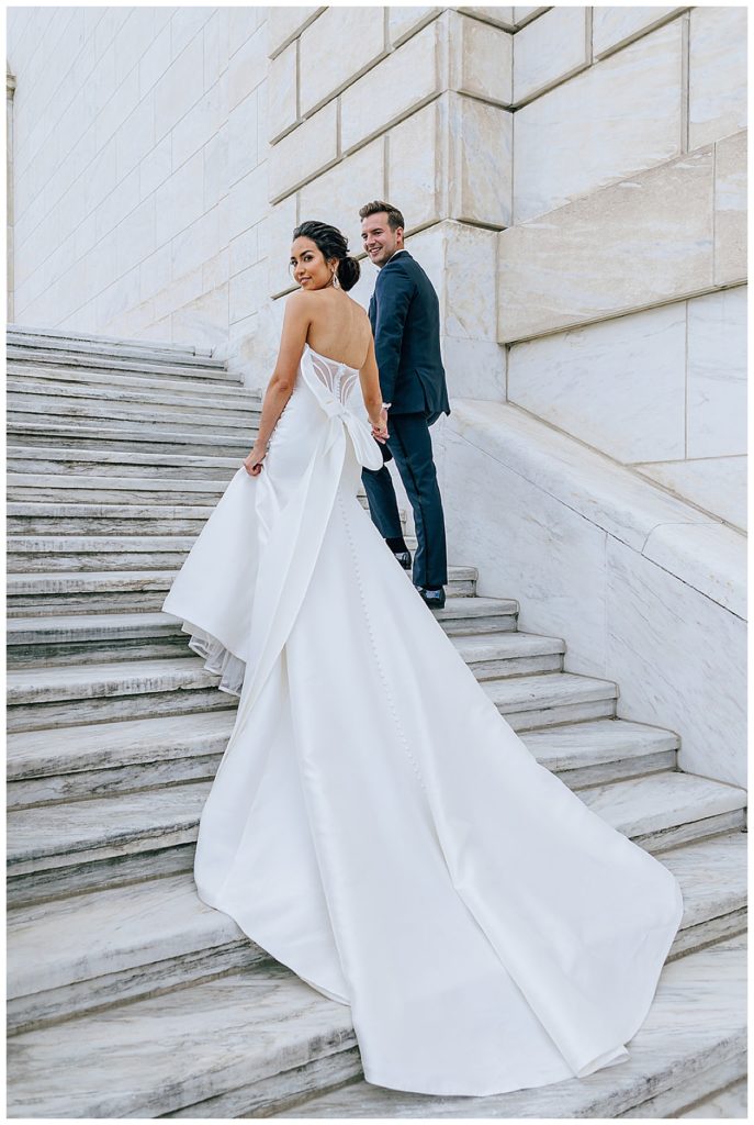 Bride and groom walk hand in hand up stairs for Kayla Bouren Photography