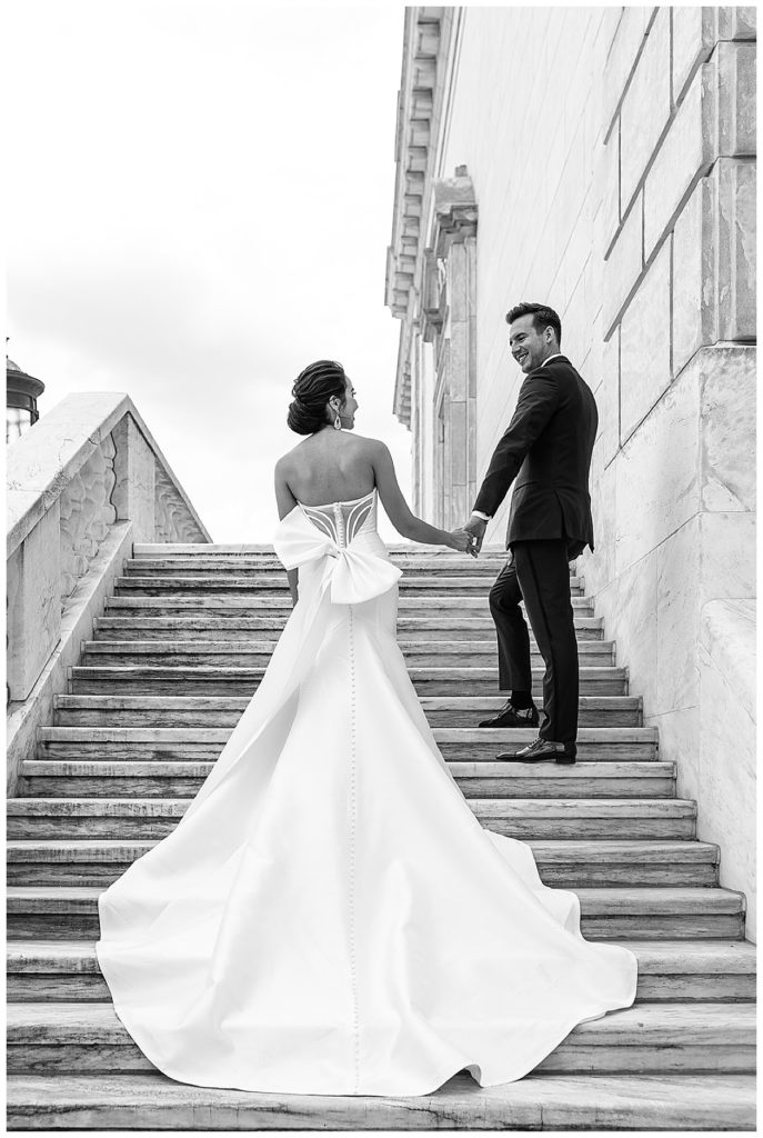 Groom holds bride's hand upstairs for Chic Detroit Wedding