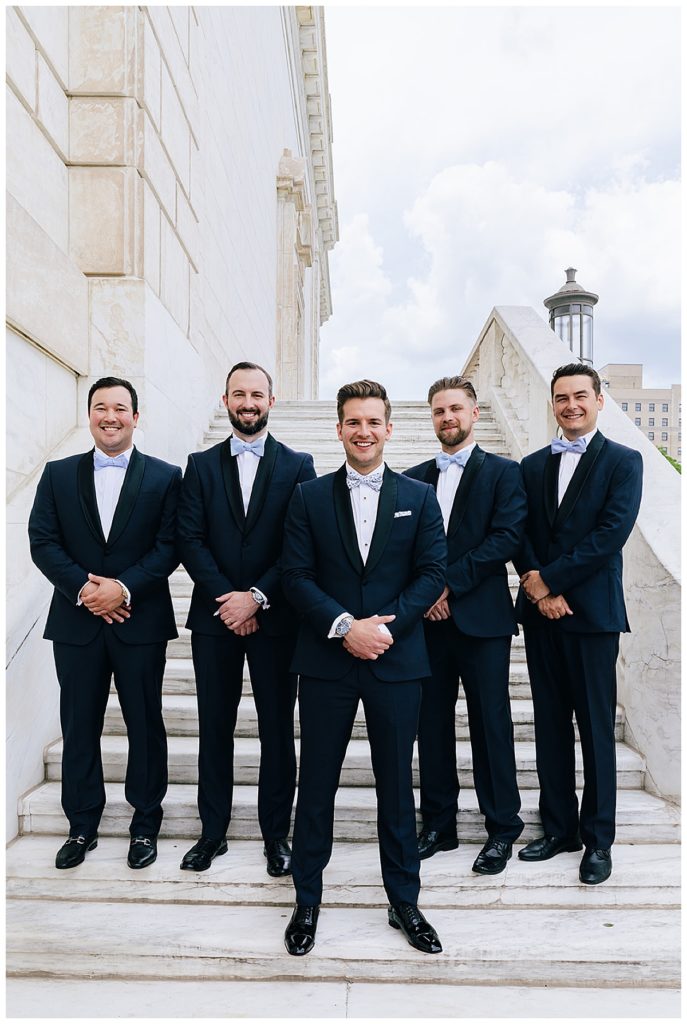 Groom and wedding attendants smile on stairs for Kayla Bouren Photography