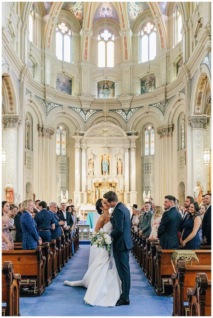 Groom and bride share kiss in aisle for Chic Detroit Wedding
