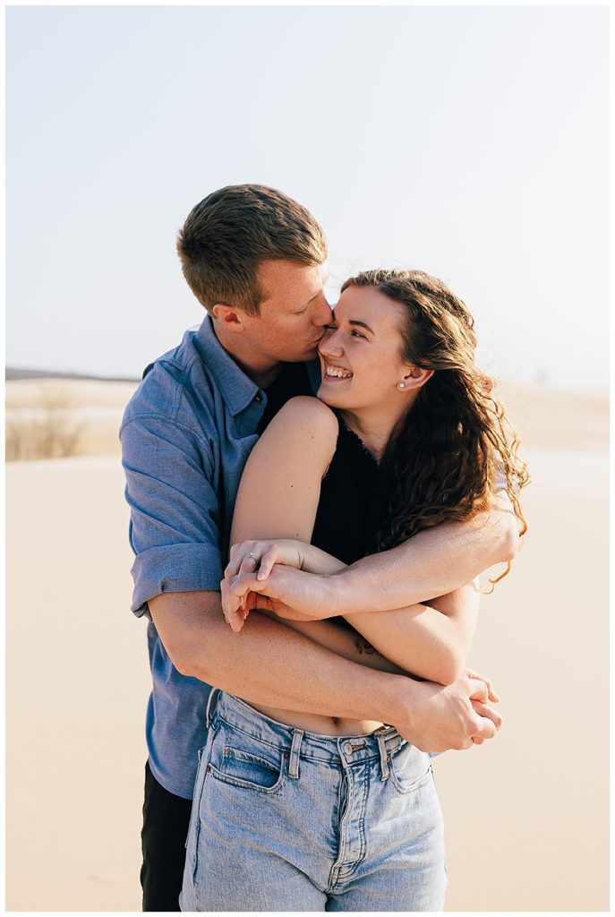 Man gives woman a kiss during Silver Lakes Sand Dunes Engagement Session.