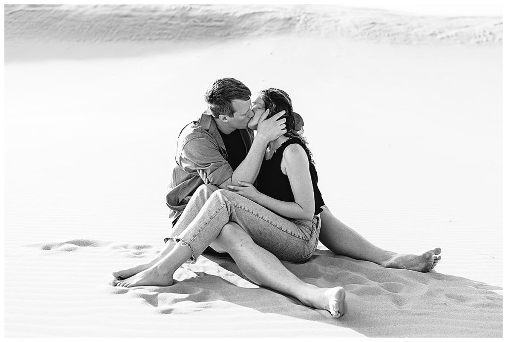 Engaged couple kissing while sitting for Kayla Bouren Photography.