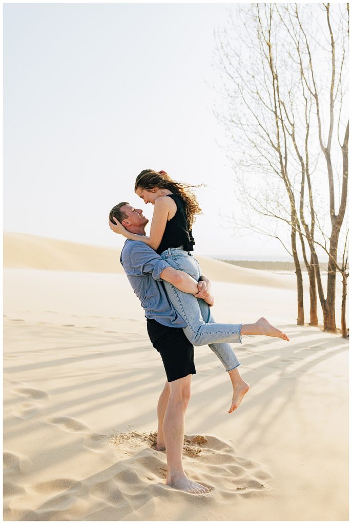 Man picks up lady for Silver Lakes Sand Dunes Engagement Session.