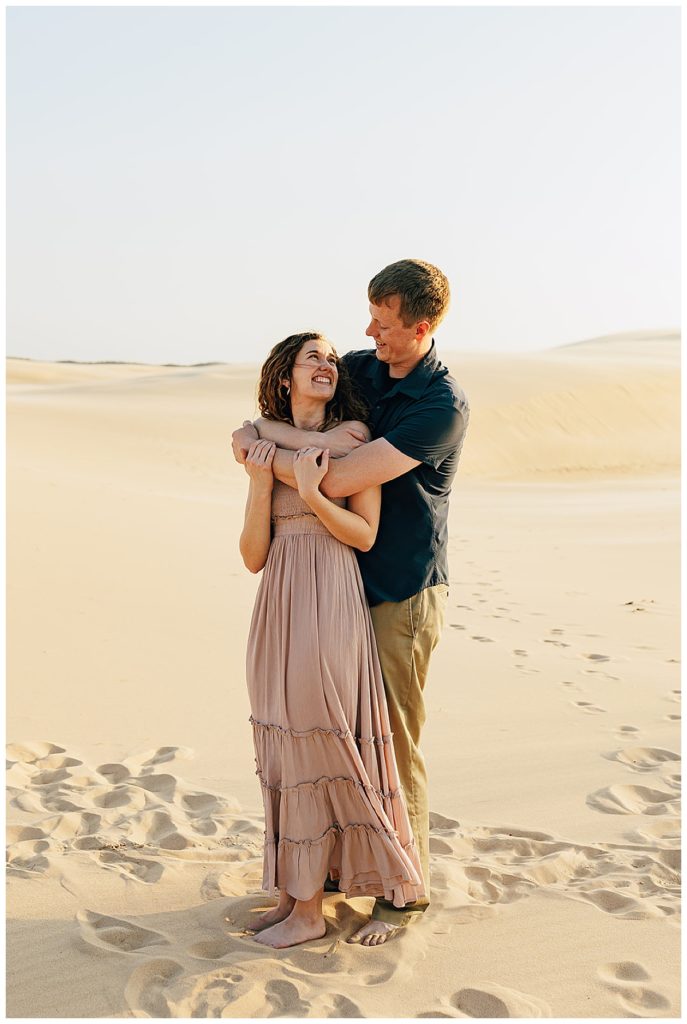Woman looks up and smiles during Silver Lakes Sand Dunes Engagement Session.