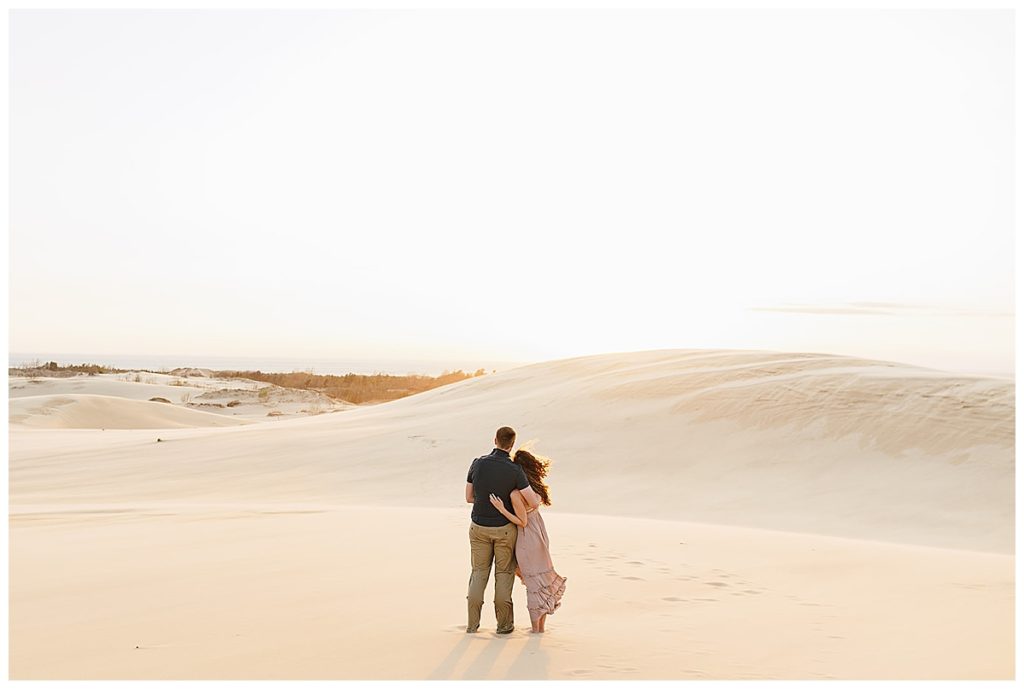 Couple glances at sand during Silver Lakes Sand Dunes Engagement Session.