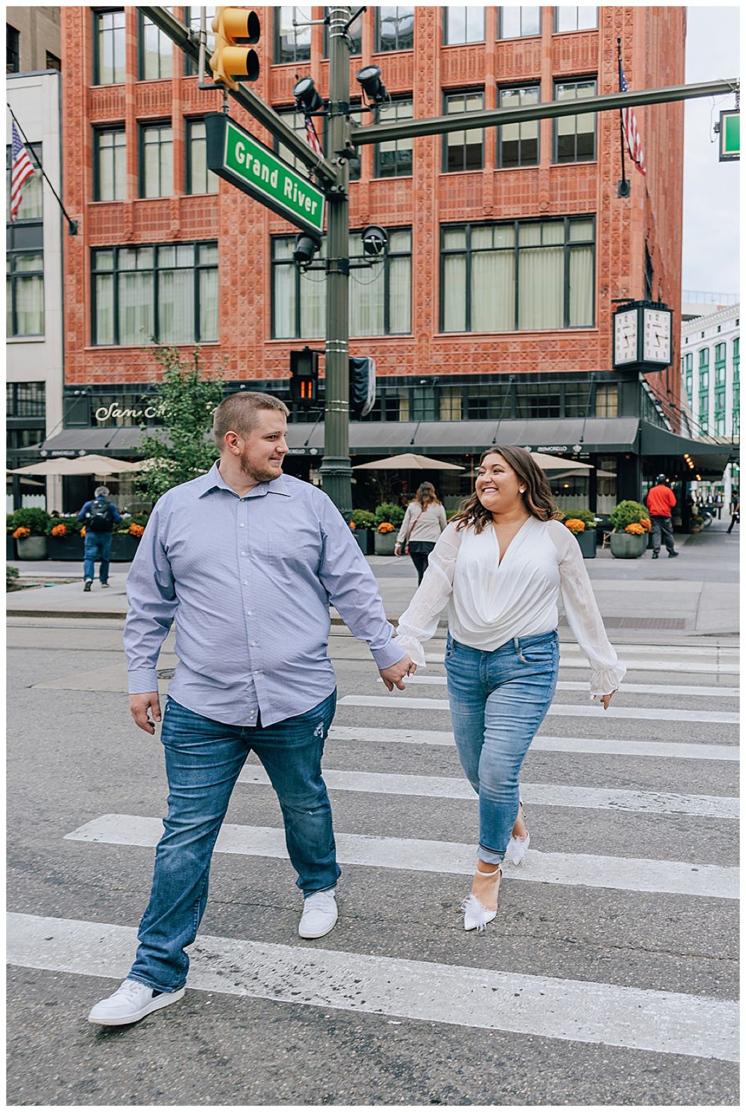 Guy holds woman's hand down street for Downtown Engagement Session