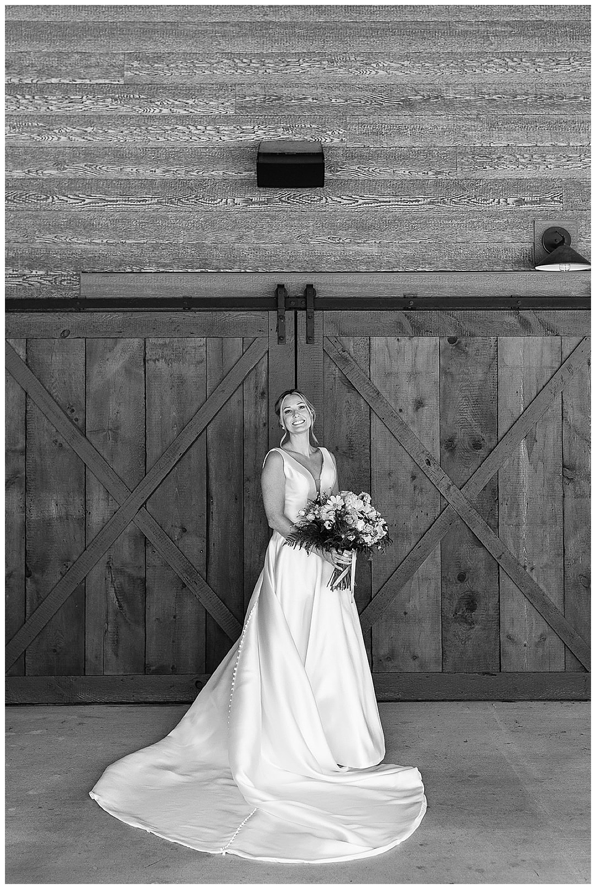 Standing in front of wooden door, bride holds flower for Kayla Bouren Photography